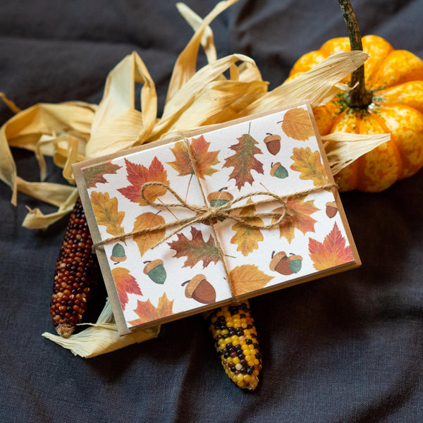 Notecards with fall leaves and acorns wrapped in twine.